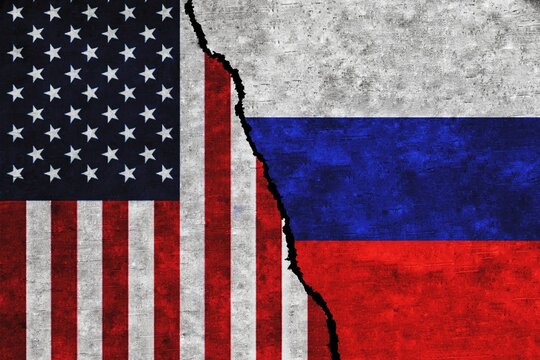 Concept of a conflict between USA and Russia with painted flags on a wall with a crack