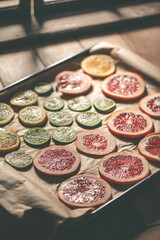 Sliced orange, tangerine and grapefruit slices on baking sheet, preparing citrus wedges for Christmas garland