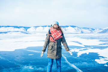 Happy smiling female traveler jumps on frozen Baikal lake during winter adventures 