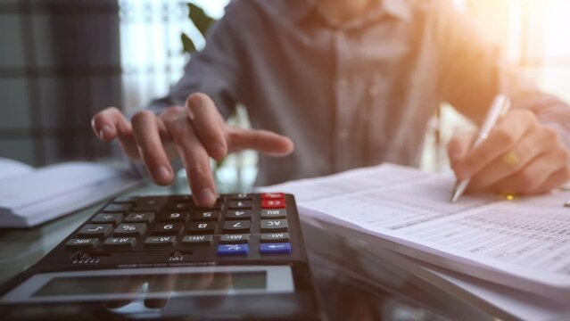 accountant working on desk using calculator for calculate finance report in office