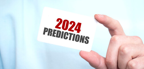 Man in blue sweatshirt holding a card with text 2024 predictions, business concept