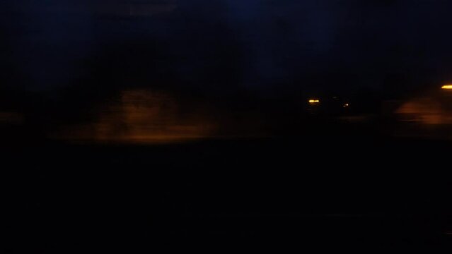 Panorama of the night city is blurred in motion. A view from the window of a train or a car on the night city in motion.