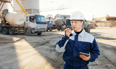 Engineer in uniform and hard hat uses radio walkie to control and coordination for effective work...