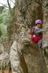Side view of a woman in purple helmet on a horizontal traverse, vertical image