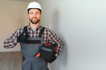 Portrait of a confident repairman with beard standing in empty apartment