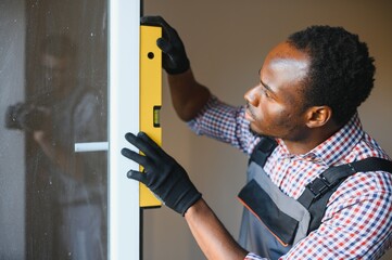 handsome young african american man installing bay window in new house construction site