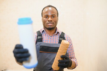 African American plumber holding new and used water filters