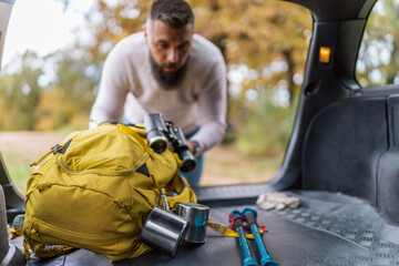 Amidst the mountainous terrain, a man in his 30s unpacks his essentials from the car, getting ready...