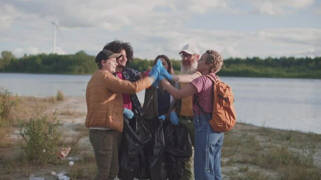 volunteers with garbage bags wearing gloves bringing hands together while cleaning a national park