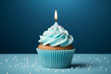 Blue cupcake on a blue background with a lit-up candle.