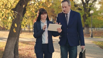 Business woman and businessman talking outdoors. Male, female company colleagues discuss business...