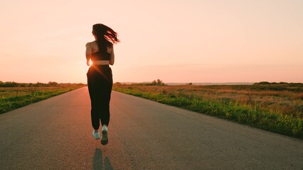 Legs of young woman run along asphalt at sunset in summer. Running after sun. Training jogging....