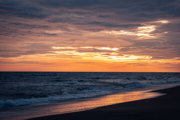 Wet surfline of black beach landscape photo. Beautiful nature scenery photography with bright sky on background