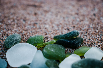 Obraz na płótnie Canvas Sand beach and glass stones concept photo. Glass stones from broken bottles polished by the sea.