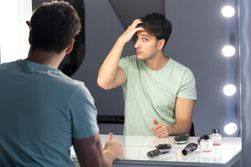 In front of the mirror, a man meticulously grooms himself, his reflection capturing the focused...