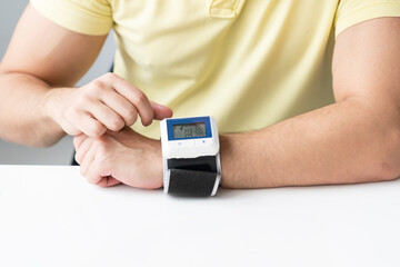 Close-up of man checks up his blood pressure and pulse by wrist tonometer	 - obrazy, fototapety, plakaty