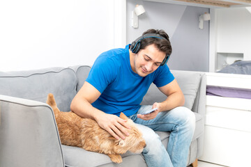 Positive guy sits on the couch and plays with his cute dog	