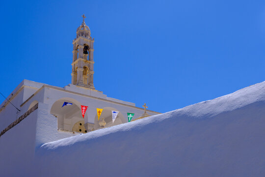 Greek church with colorful fags over blue sky on Tinos Island