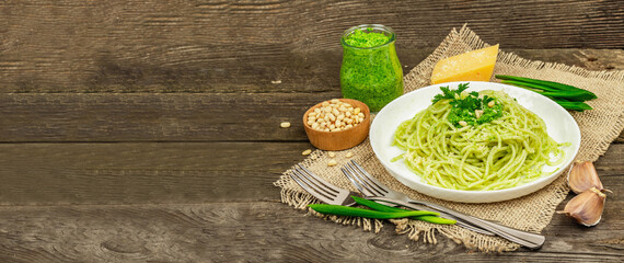 Spaghetti pasta with pesto sauce and fresh ramson leaves. Cutlery, parmesan, pine nuts. Rustic style
