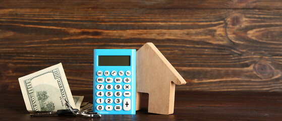 Calculator, figure of house, keys and dollar banknotes on wooden background with space for text