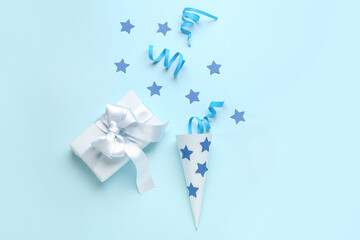 Party cone with serpentine, stars and gift on blue background