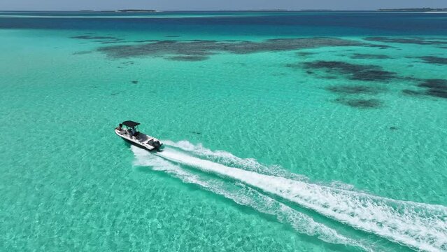 Maldives paradise unfolds with a turbo yacht cruising over crystal waves, offering stunning aerial footage, featuring a girl on the yacht's bow