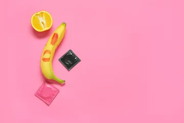 Fotobehang Fresh banana with lipstick kiss, orange and condoms on pink background. Sex education concept © Pixel-Shot