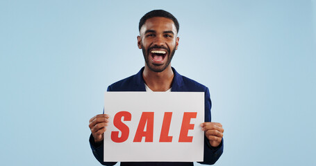 Excited man, portrait and sale sign for advertising, deal or discount against a blue studio...