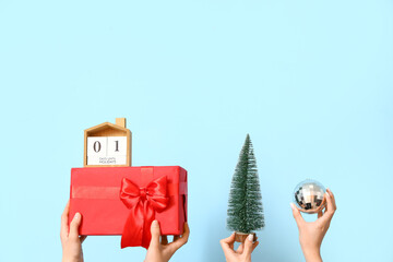Women with gift, fir tree and ball on blue background. New Year celebration