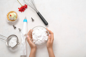 Female confectioner cooking tasty cakes on white background