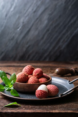 Bowl of ripe lichee fruit (Litchi chinensis) on wooden background
