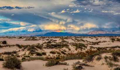 Fototapeta na wymiar Storm and rainbow in the distance at White Sands New Mexico