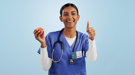 Happy woman, portrait and doctor with thumbs up for apple, health or diet against blue studio...
