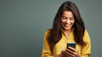Young woman smiling and holding her smartphone on a colored background