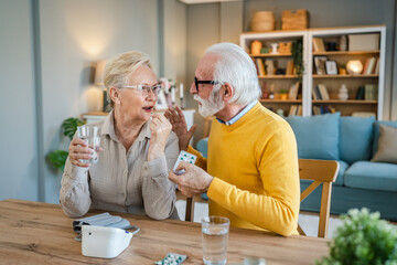 senior couple at home woman take medicine while her husband sit beside