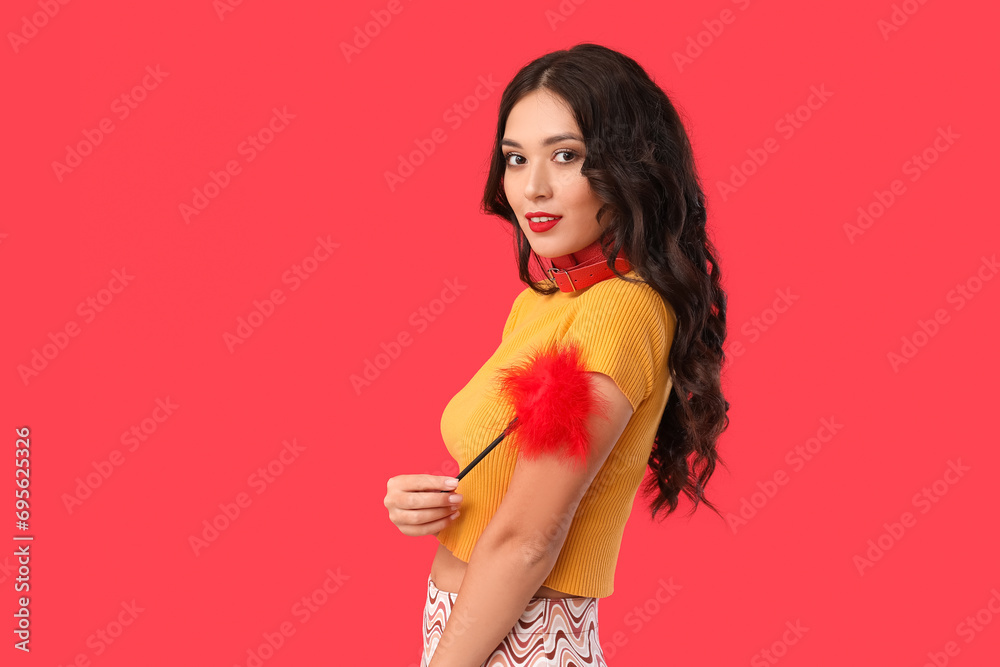 Canvas Prints Beautiful young sexy Asian woman with feather stick and collar on red background