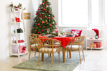 Stylish interior of festive living room with Christmas tree and served dining table