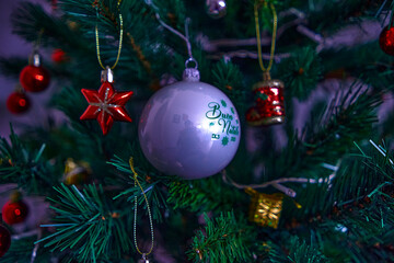 Palla di natale bianca con scritta verde su albero di natale