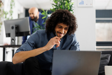 Smiling entrepreneur checking sales revenue growth on laptop while working in business office....