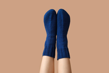 Legs of young woman in warm blue socks on beige background
