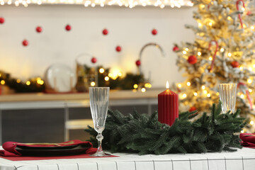 Beautiful table setting with wreath and candle for Christmas dinner in kitchen