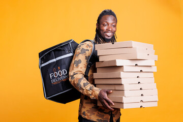 Pizzeria courier holding boxes full with pizza, delivering takeaway food orders to customers during...