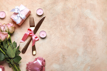 Beautiful cutlery for Valentine's Day with pink roses, gift and candles on beige grunge background