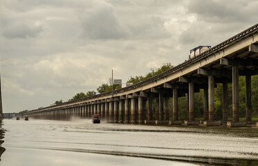 Airboats traveling alongside I-10 interstate bridges over the bayou of Atchafalaya basin near Baton...