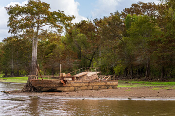 Rusting abandoned boat on the banks by calm waters of the bayou of Atchafalaya Basin near Baton...
