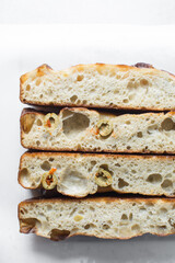 homemade olive focaccia on a white background, Flatlay of focaccia with green olive topping, fresh homemade focaccia bread