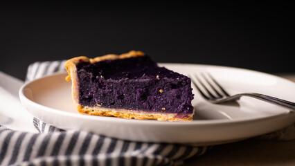 Purple yam pie on a white ceramic plate with fork.