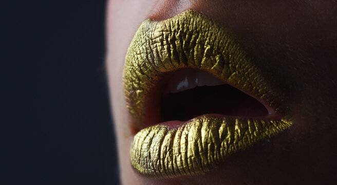 Gold lips. Gold paint on mouth. Golden lips. Luxury gold lips make-up. Golden lips with creative metallic lipstick. Gold metal lip. Sensual woman mouth, clse up, macro.