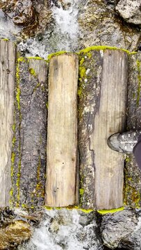 Slow motion 4K video POV view of Man's legs in trekking boots crossing mountain creek by wooden bridge during Makalu Barun National Park trek in Nepal. Mountain hiking and active people concept image.