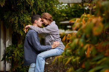 Fototapeta premium Love's Moments: A Young Cute Female Hugs Her Boyfriend in the Enchanting Autumn Park - A Lovestory Unfolding. Young Cute Female Hugs Boyfriend. In Autumn Outdoor. Lovers Walking in Park. Attractive